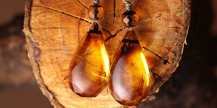 Un par de aretes hechos de ámbar sobre un trozo de madera en un negocio de productos de ámbar.