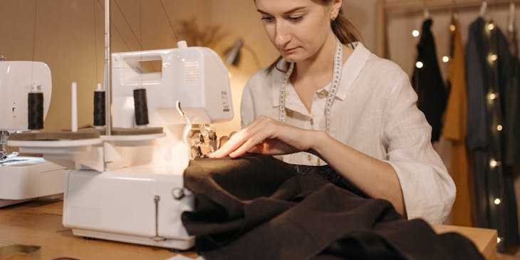 Un sastre cosiendo una prenda con una máquina de coser.