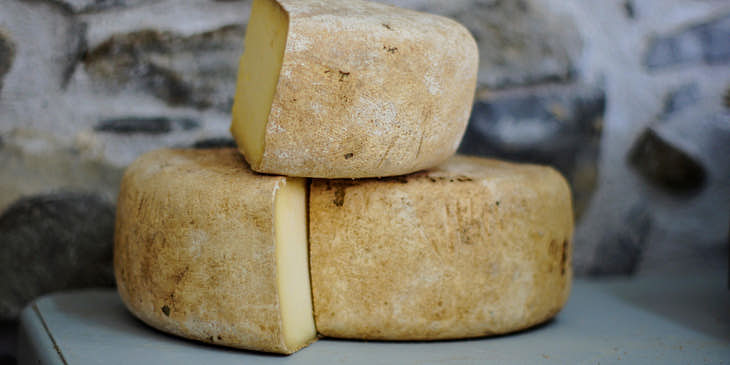 Una rueda de queso de tafí cortada en tres partes sobre un aparador en un negocio de queso de tafí.