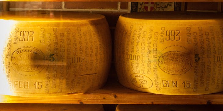 Ruedas de queso reggianito apiladas una encima de la otra en el aparador de un negocio de queso reggianito.