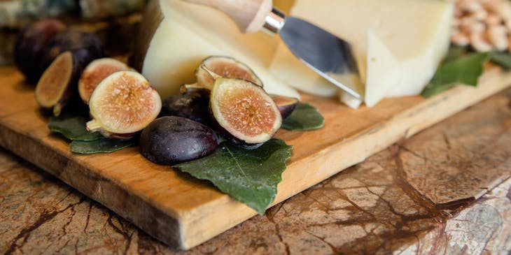 Higos en rodajas gruesas a un lado de cortes de queso sardo sobre una tabla de madera en un negocio de queso sardo.