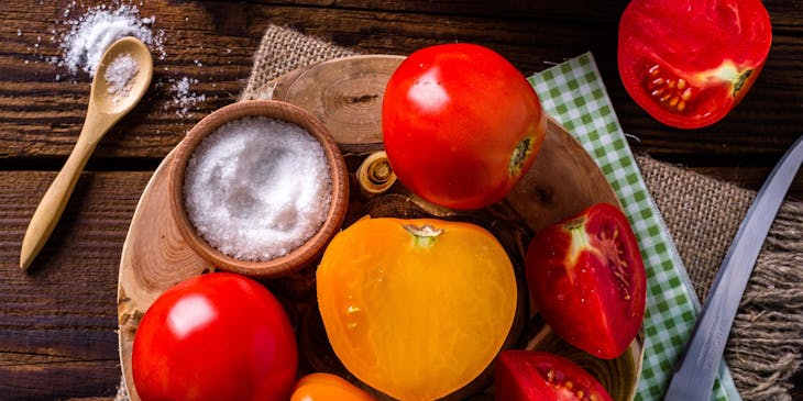 Pimentón, tomate y un cuenco con sal sobre una mesa de madera en un negocio de quiquirimichi.