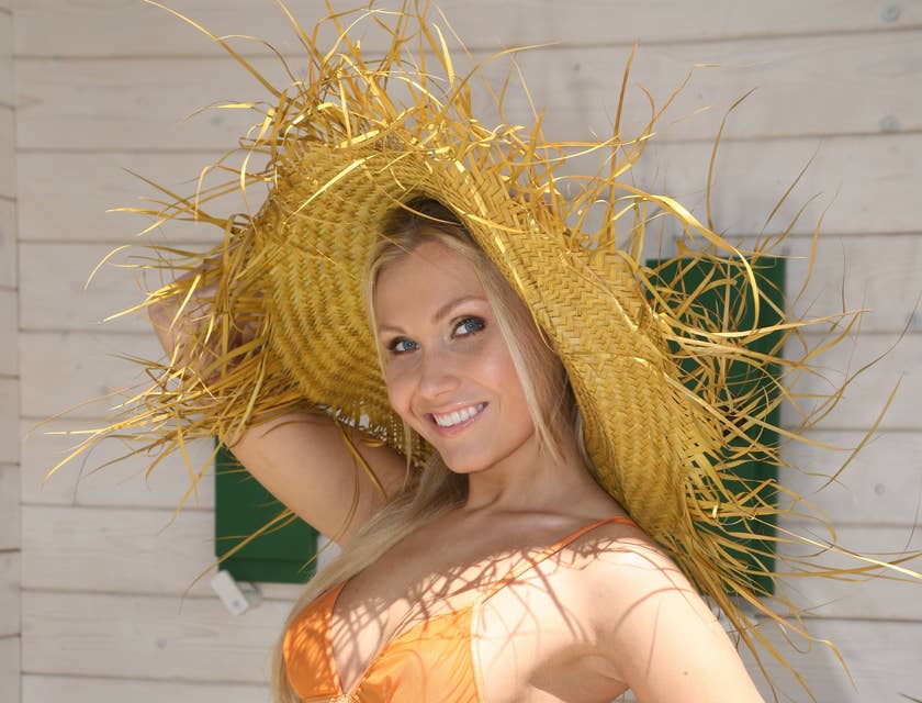 Una mujer en ropa de playa con un sombrero de pava en un negocio de sombreros de pava.
