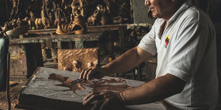 Un escultor trabajando en madera en el taller de un negocio de talla de madera.