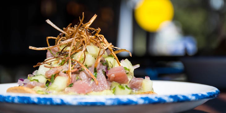 Una tostada preparada con atún, aguacate y cebolla frita en un negocio de tostadas.