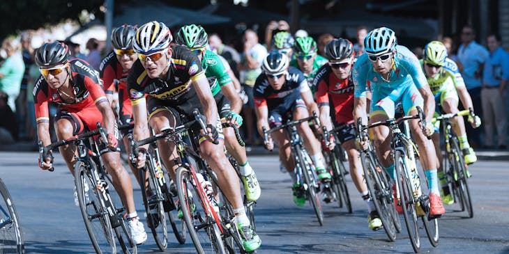 Grupo de ciclistas pedaleando en una carrera para una página deportiva.