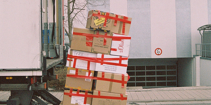 Cajas de cartón apiladas una sobre otra a punto de ser subidas a un camión de paquetería.