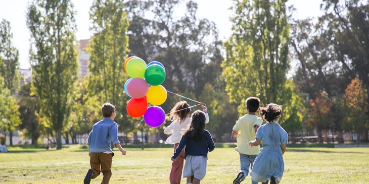 Un grupo de cinco niños jugando con unos globos en un parque recreativo.