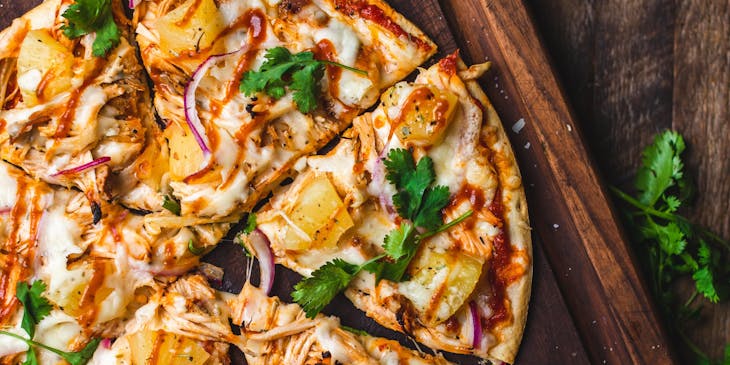 Una pizza completa sobre una tabla de madera oscura en una pizzería de fugazzeta.