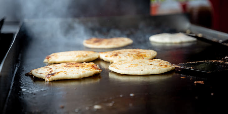 Pupusas sobre un comal en una pupusería.