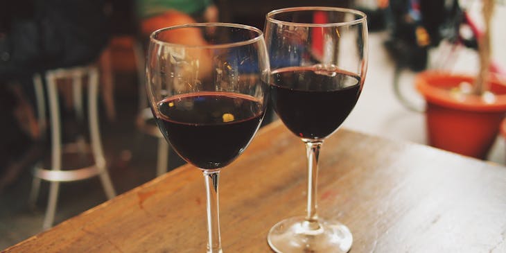 Dos copas servidas con vino tinto sobre una mesa de madera en un restaurante andaluz.