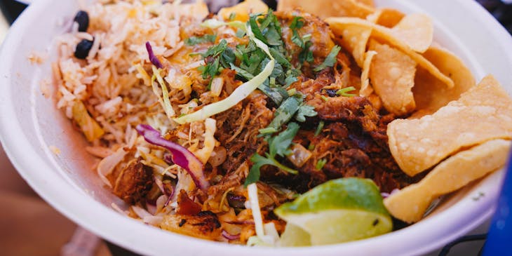 Un plato con cochinita pibil, totopos y arroz en un restaurante de comida yucateca.