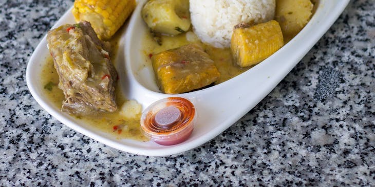 Plato de sancocho servido en una vajilla blanca sobre una mesa en un restaurante de sancocho.