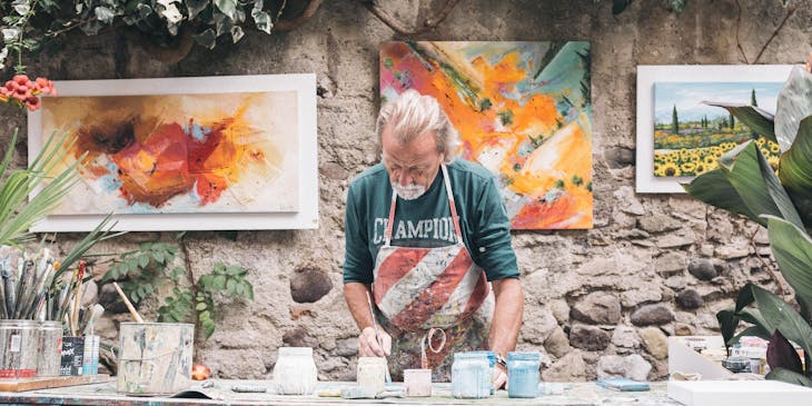 Artesano trabajando sobre una mesa con pinturas en la pared en un taller de artesanos.