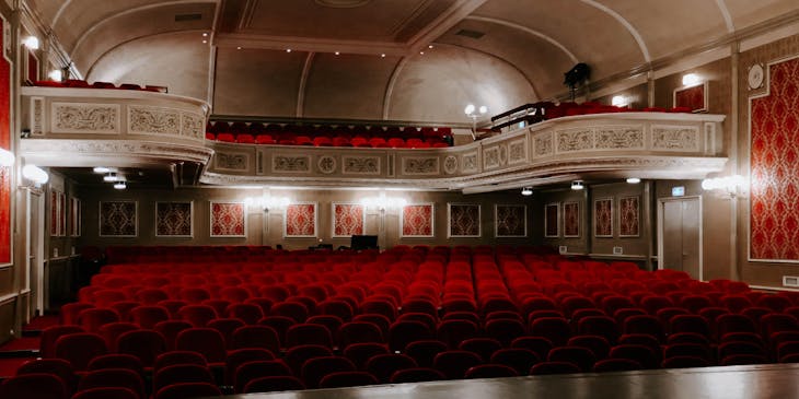 Vista de butacas rojas desde el escenario de un teatro.