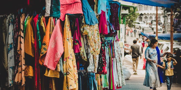 Distintas prendas colgadas en una tienda de ropa de paca.