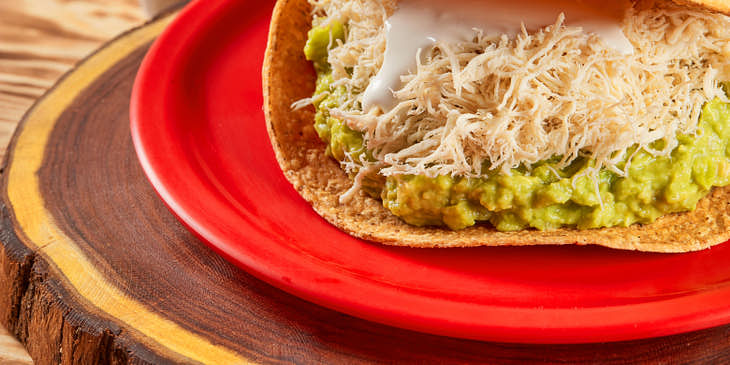 Una tostada gigante de pollo, crema y aguacate en una tostadería.