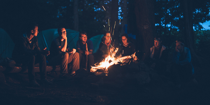 Jovens em volta de uma fogueira em um acampamento evangélico.