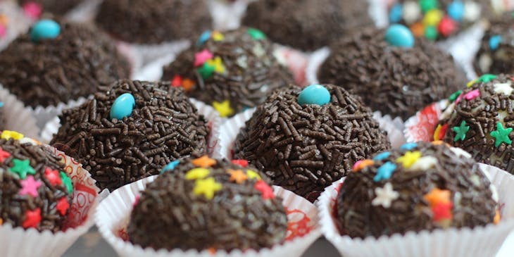 Diversos brigadeiros cobertos com granulados em uma brigaderia