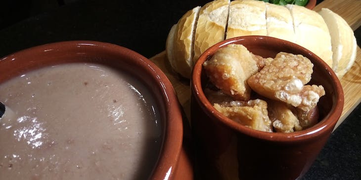 feijão, torresmo e pão em uma mesa de um restaurante de comida mineira.