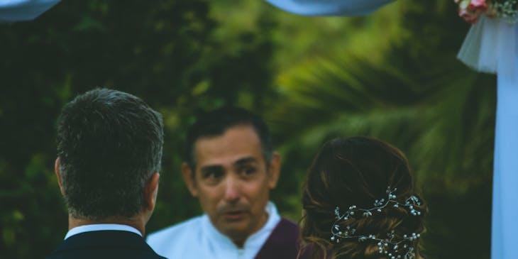 Bridal couple standing in front of an officiant.