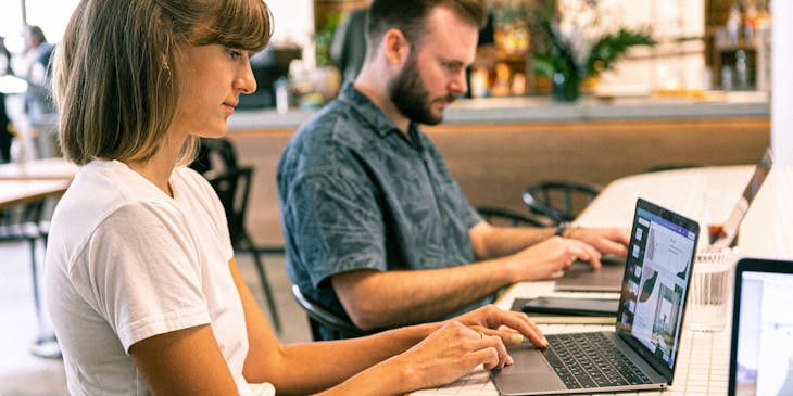 Two people typing on laptops at an online business.