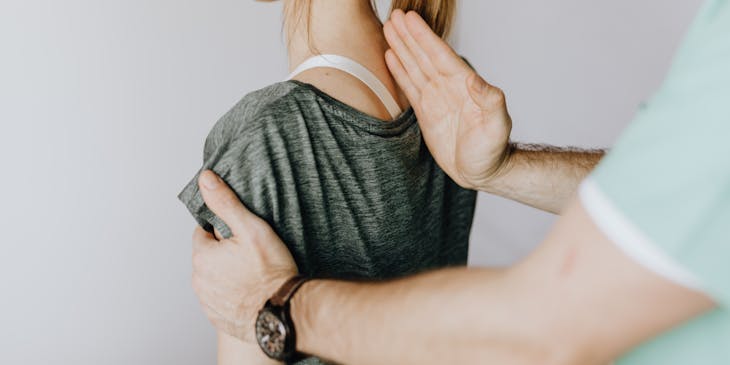 Osteopathic physician treating a woman with upper back pain.