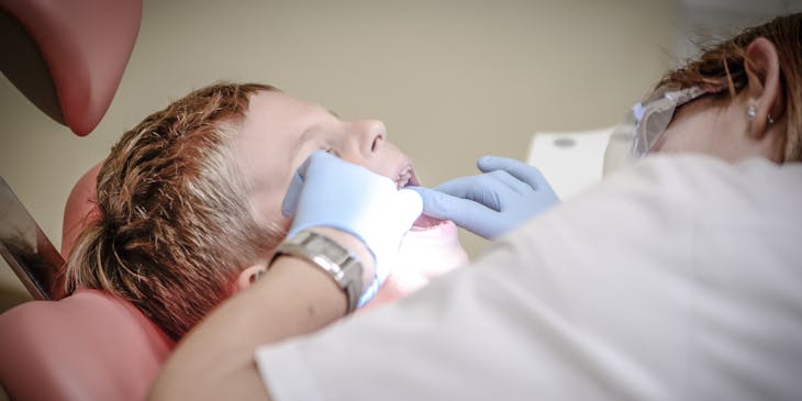 Un ou une dentiste pédiatrique effectuant des soins dentaires sur un jeune patient.