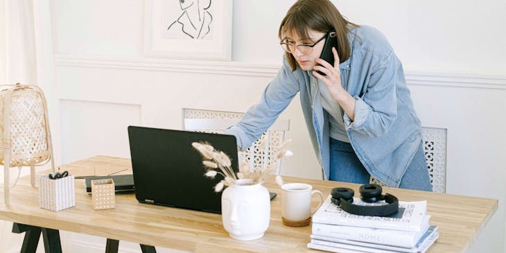 A personal concierge checking her laptop while talking on the phone.