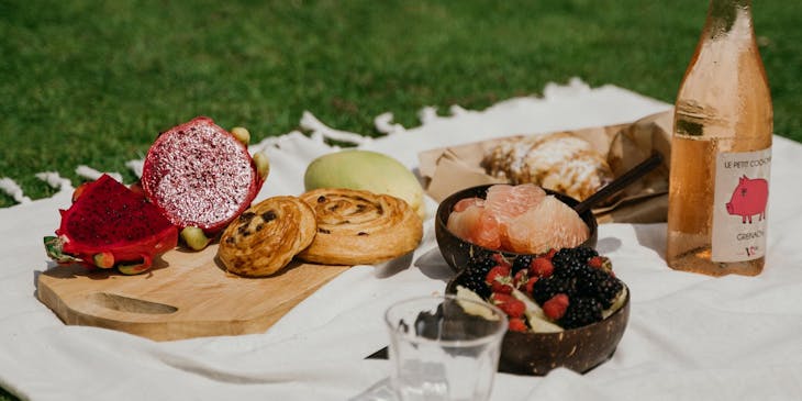 Alimentos preparados por un negocio de picnic extendidos sobre una manta en el césped.