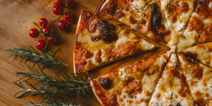 Pizza on a cutting board with herbs.