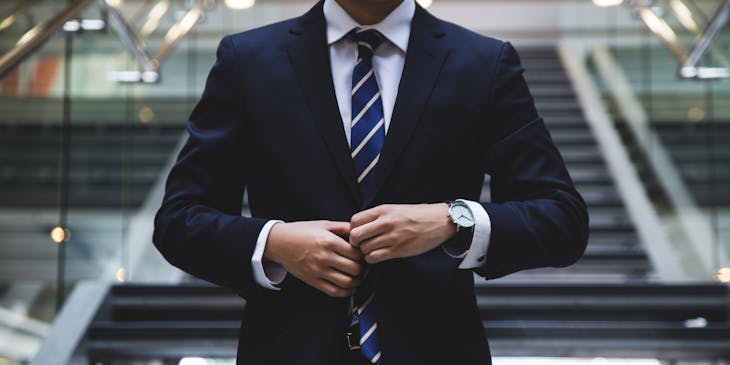 Man in a suit buttoning his jacket.