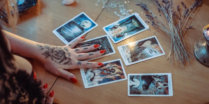 Um médium lendo cartas de tarot em cima de uma mesa com cristais.