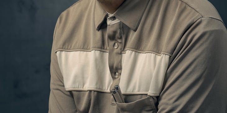 Homem piscando para foto usando uma camiseta cinza.