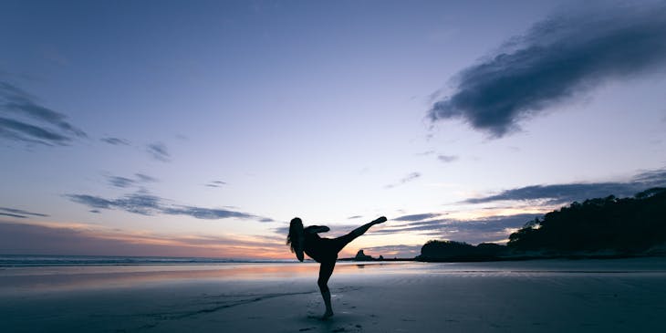 Mulher praticando qi gong em uma praia.