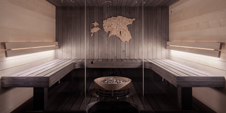 Sauna com painéis de madeira em volta da estufa e decoração de cortiça na parede.