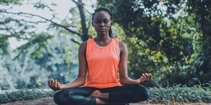 Mulher praticando autocuidado meditando ao ar livre.