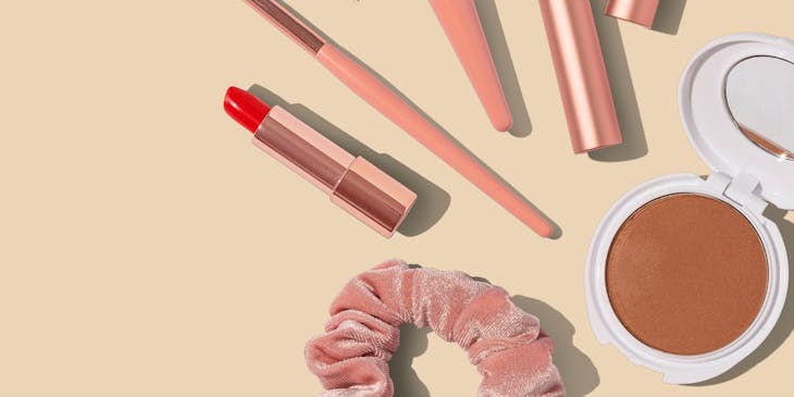 Des produits de maquillage sur une surface rose.