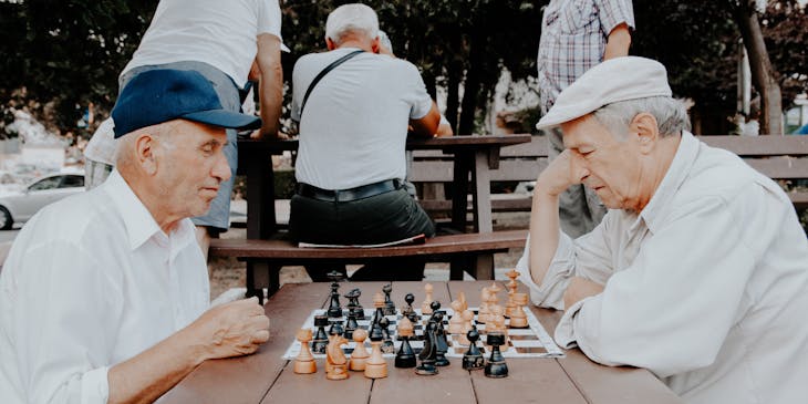 Two seniors playing chess in a park.