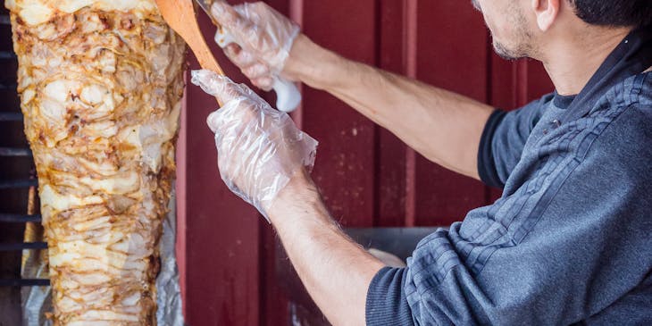 Un homme coupe des morceaux de viande pour en faire un shawarma.