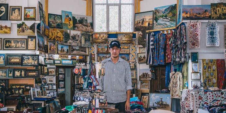 Un homme avec une casquette entouré de bibelots dans un magasin de souvenirs.