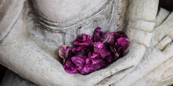 Purple flowers held on a statue's lap.