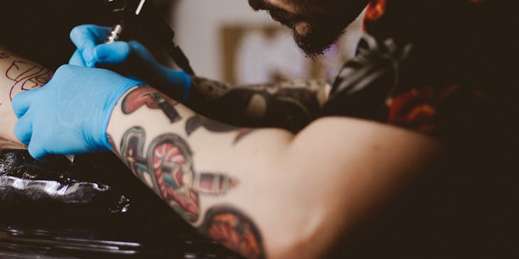 Persona tatuando a alguien en un negocio de tatuajes.