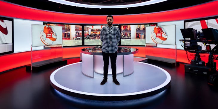 A man standing inside a television station. news studio