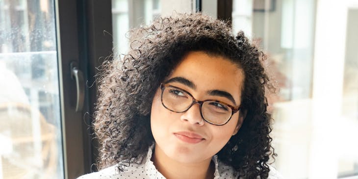 Una mujer que parece pensativa mientras toma notas en su libro.