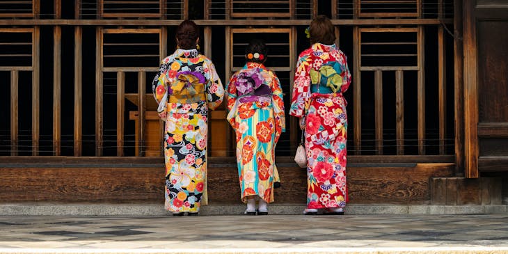 Tres mujeres japonesas vistiendo sus ropas tradicionales frente a la puerta del templo