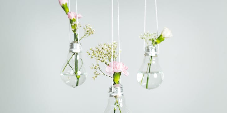 An assortment of upcycled flower vases hanging from the ceiling.