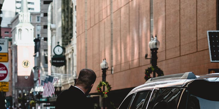 A valet standing next to a parked car.