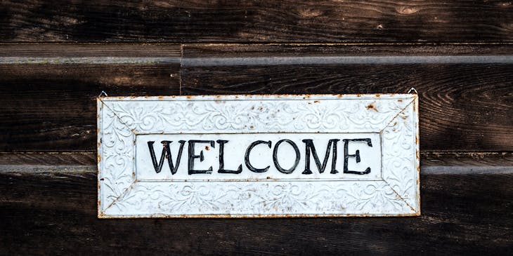 A white welcome sign on a dark wooden background greeting visitors.