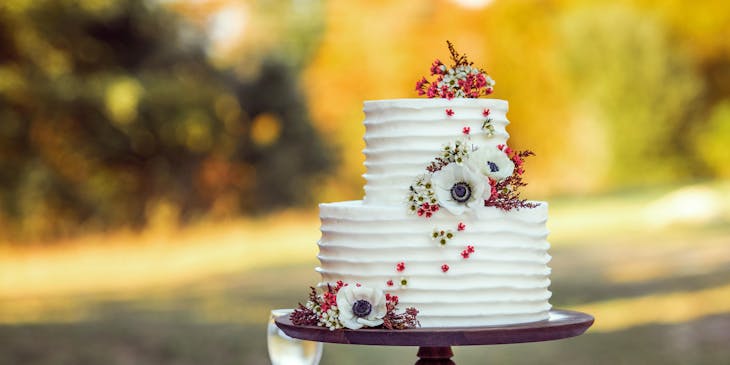 Un pastel con betún blanco, adornado con flores en un negocio de pasteles de boda